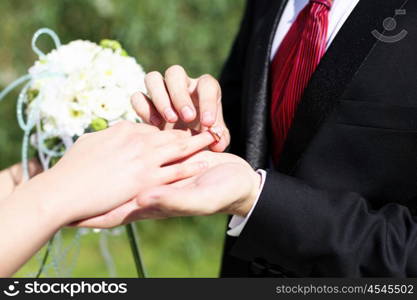 Shot moment when the groom puts the ring on a young bride&#39;s hand.