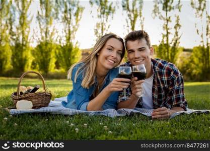 Shot of a beautiful couple on the park making a picnic and drinking wine