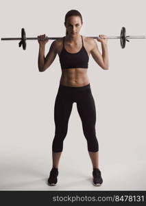 Shot of a beautiful young woman in a workout gear lifting weights