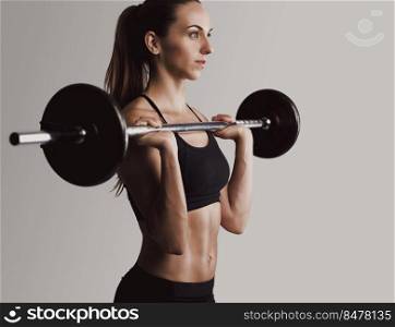 Shot of a beautiful young woman in a workout gear lifting weights
