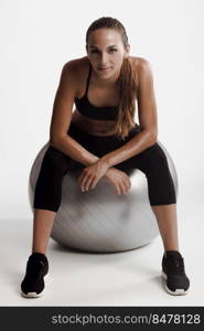 Shot of a beautiful young woman sitting on swiss ball after the train
