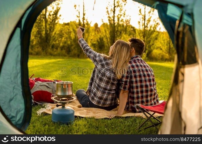 Shot of a happy couple c&ing on the nature and making a selfie