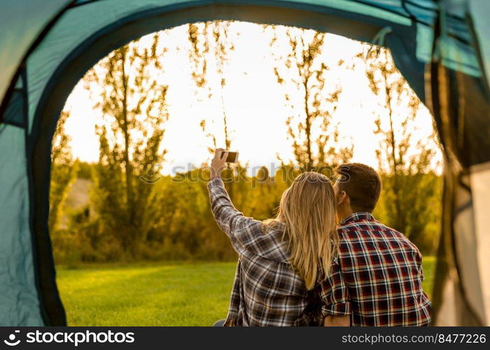 Shot of a happy couple c&ing on the nature and making a selfie