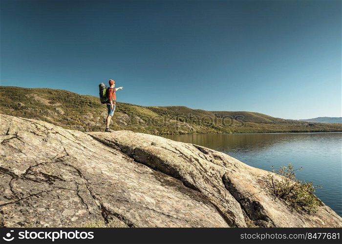 Shot of a man pointing to the beautiful view of the lake 
