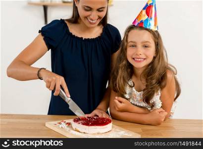 Shot of a mother and daughter cuting the cutting the birthday cake