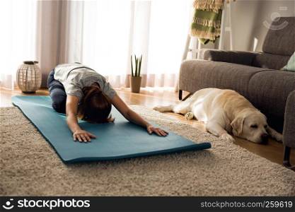 Shot of a woman doing exercise at home with her dog