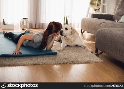 Shot of a woman doing exercise at home with her dog