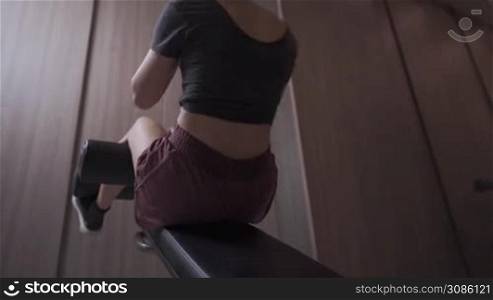 Shot of fit woman doing abdominal crunches on incline bench, self body conditioning, building six packs muscles tension, evening shot, gym fitness center, muscular female working out alone in the gym