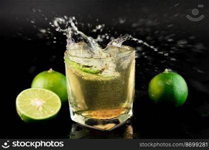 Shot of golden Mexican tequila with lime and salt on black background. A glass of tequila with lemon slices and splashing. Alcoholic drink concept. selective focus.