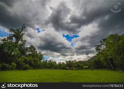 shot of green field with dramatic rainy clouds