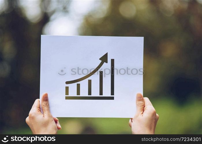 Show business paper graph statistics,arrow showing the chart in hand on nature background