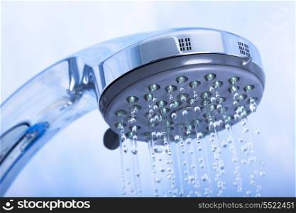 Shower head with running water on blue background