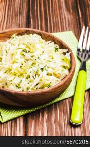 Shredded fresh cabbage with dill in a wooden bowl