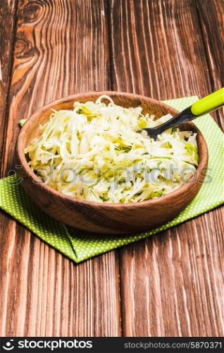 Shredded fresh cabbage with dill in a wooden bowl