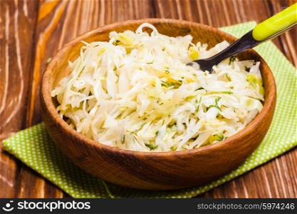 Shredded fresh cabbage with dill in a wooden bowl. The cabbage salad