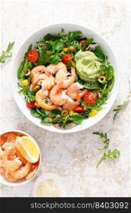 Shrimp and leafy vegetables salad with tomato, bell pepper, olive and avocado sauce. Top view
