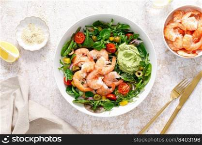 Shrimp and leafy vegetables salad with tomato, bell pepper, olive and avocado sauce. Top view