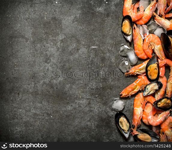 Shrimp and mussels with ice. On a stone background.. Shrimp and mussels with ice.