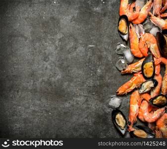 Shrimp and mussels with ice. On a stone background.. Shrimp and mussels with ice.