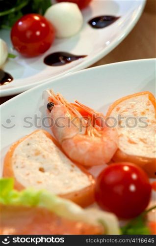 Shrimp and salmon mousse alongside tomato, mozzarella and rocket salad with olive oil and balsmaic vinegar dressing shot in golden sunshine