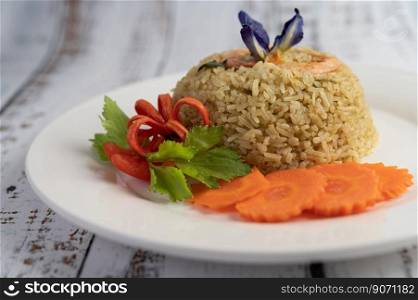 Shrimp fried rice on a white plate consisting of tomatoes and carrots.