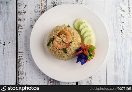 Shrimp fried rice on a white plate consisting of tomatoes and cucumbers.