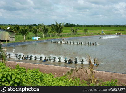 Shrimp hatching pond under cloudy sky at Mekong Delta, Vietnam, engine rotate to make O2 for shrimp, shrimp lake among Viet Nam countryside