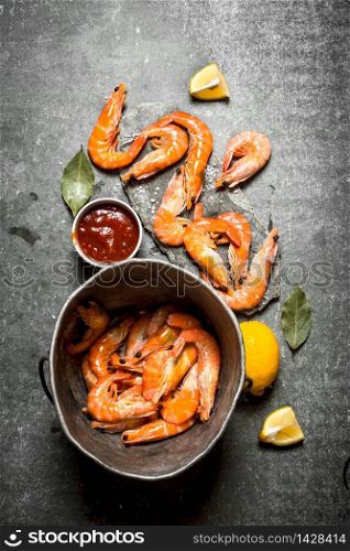 Shrimp in an old pot with sauce and spices. On a stone background.. Shrimp in an old pot with sauce and spices.
