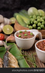 Shrimp paste, mackerel, fried on banana leaves, chili, tomato, garlic and lemon on wooden floor.