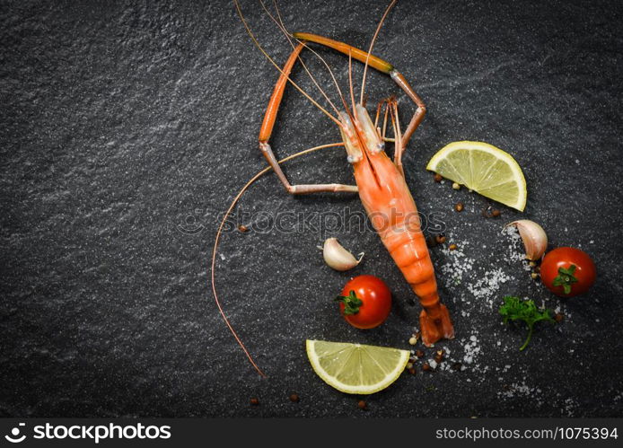 Shrimp prawn cooked shellfish seafood with lemon tomato herbs and spices on dark background