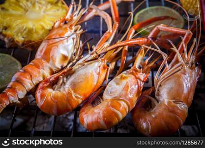 shrimp,prawn grilled on barbecue stove with lemon and pineapples