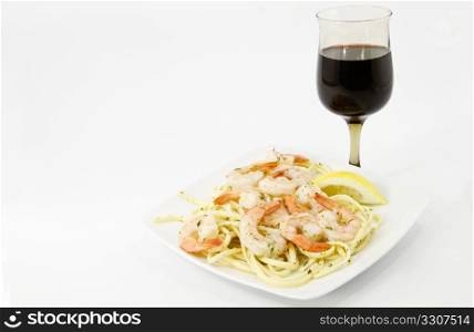 Shrimp scampi with herbs and lemon slice are served over olive tossed spaghetti with healthy red wine