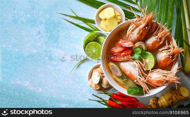 Shrimp soup on seafood soup bowl with thai herb and spices, Hot and sour spicy shrimps prawns soup  curry lemon lime galangal red chili straw mushroom on table food, Thai Food Tom Yum Kung - top view