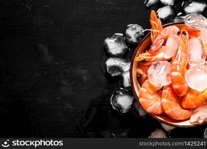 Shrimp with ice in a bowl. On the black board.. Shrimp with ice in a bowl.
