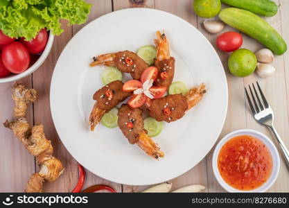 Shrimp wrapped pork cutlets arranged beautifully with cucumbers and tomatoes in a beautiful white dish.