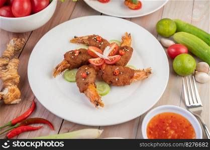 Shrimp wrapped pork cutlets arranged beautifully with cucumbers and tomatoes in a beautiful white dish.