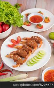 Shrimp wrapped pork cutlets arranged beautifully with cucumbers and tomatoes in a beautiful white dish.
