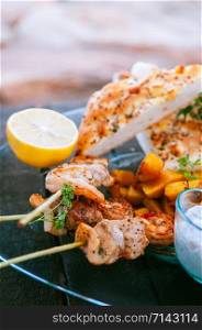 Shrimps and chicken Piri Piri African style Barbecue skewers with flatbread on glass plate close up image
