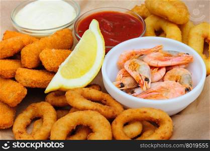 Shrimps, calmar rings and fish sticks with lemon and dip sauces, served as beer snacks
