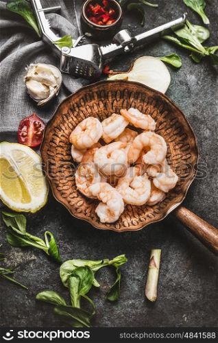 Shrimps in fried pan on rustic kitchen table background with cooking ingredients, top view