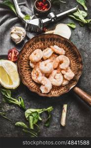 Shrimps in fried pan on rustic kitchen table background with cooking ingredients, top view
