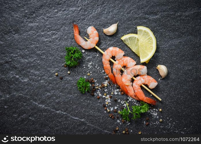 Shrimps prawns in skewer sticks seafood cooked with herbs and spices on dark background
