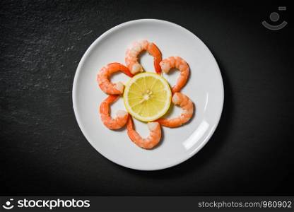 Shrimps prawns served decorate seafood plate and lemon on dark background