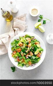 Shrimps salad with green lettuce, cucumbers and avocado, dressed with lime juice, healthy and tasty food, top view