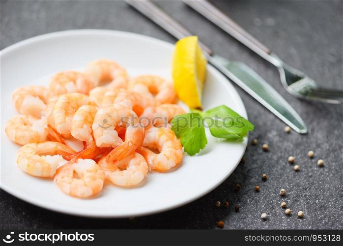 shrimps served on plate with Lemon, Herb, Pepper on white plate / boiled peeled shrimp prawns cooked in the restaurant