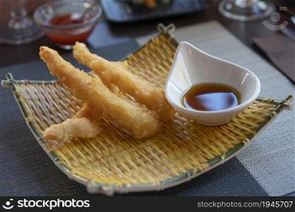 Shrimps tempura with soy sauce on yellow bamboo plate. Seafood tempura dish of traditional asian cuisine