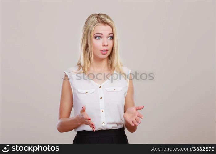 Shrugging woman in doubt doing shrug, attractive confused girl gesturing do not know sign on gray background