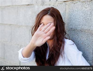 Shy brunette girl covering her face with a grey wall of background