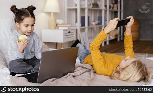 siblings bed watching video laptop mobile
