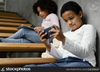 siblings home using mobile tablet